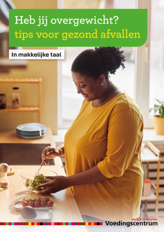 dame in geel ruimvallend shirt met overgewicht die een salade maakt in de keuken